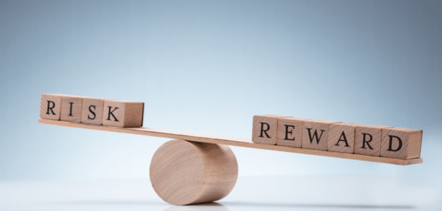Picture of block letters spelling “risk” and “reward” balancing on opposite ends of a board.